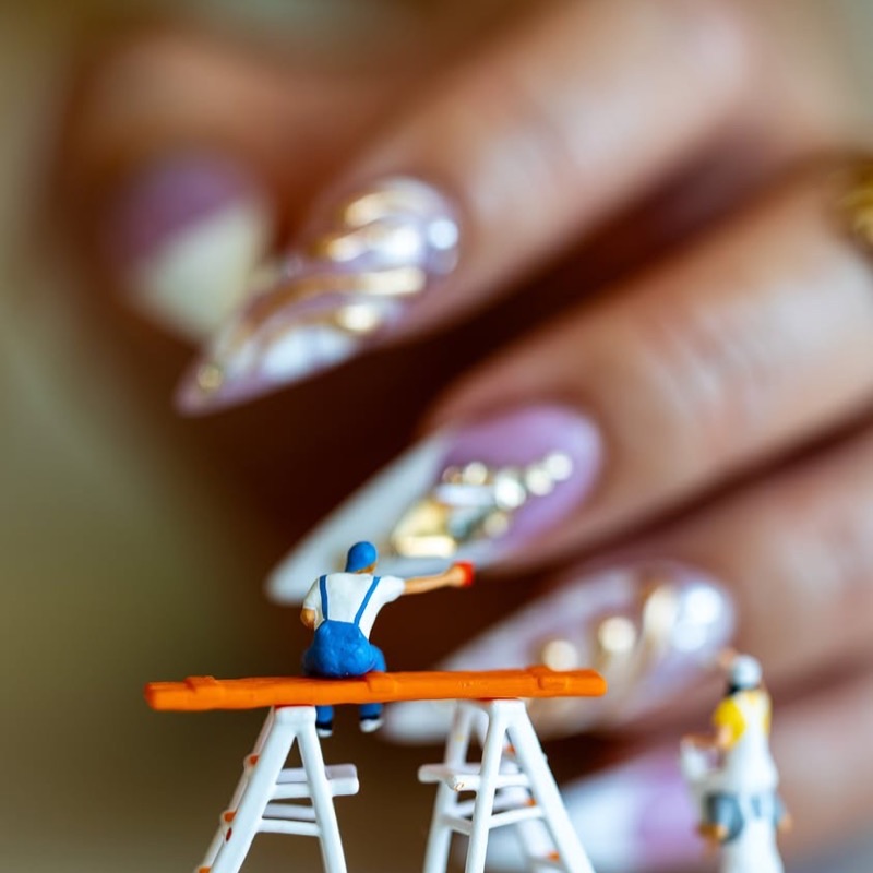 Uñas stiletto con acabado cromado y detalles dorados